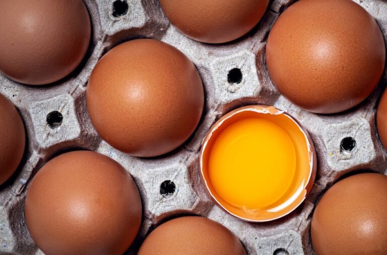 Fresh brown eggs with one broken, showcasing yolk, in a carton from Cebu City.