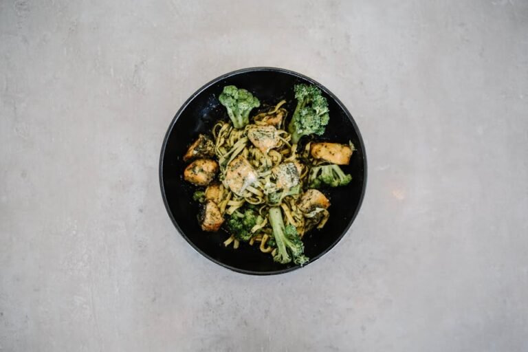 Top view of a tasty broccoli and chicken pasta in a black bowl, perfect for healthy dining visuals.