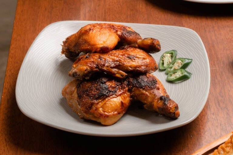 Spicy grilled chicken drumsticks on a plate with jalapeno slices.