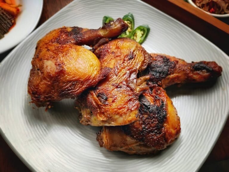 Succulent grilled chicken drumsticks served with sliced green chili peppers on a plate.
